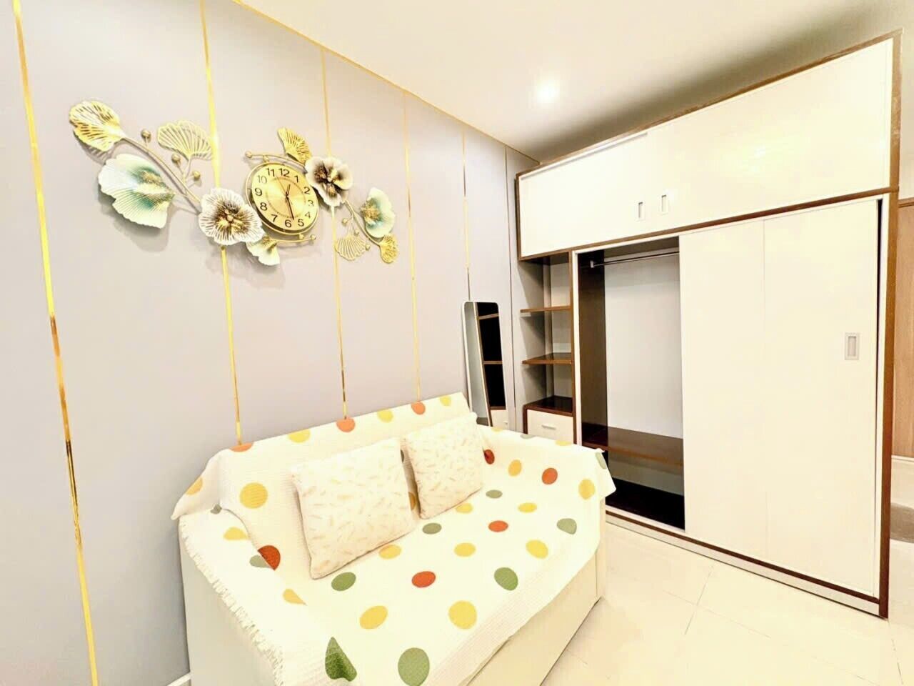 Une chambre moderne avec un canapé blanc, une grande armoire et des œuvres d’art décoratives au mur.