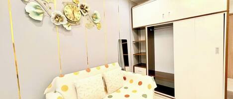 Une chambre moderne avec un canapé blanc, une grande armoire et des œuvres d’art décoratives au mur.