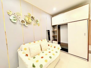 Moderni makuuhuone, jossa on valkoinen sohva, suuri vaatekaappi ja koristeellinen seinätaide.