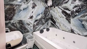 A bathroom with a marble wall, a bathtub, a sink, and a toilet. - Hotel Lee Prime (Ahmedabad)