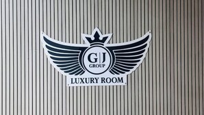 A logo with "GJ GROUP" and "LUXURY ROOM" on a vertical striped wall. - Hotel Lee Prime (Ahmedabad)