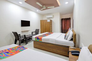 Una habitación de hotel con cama, escritorio, silla, armario y ventilador de techo.