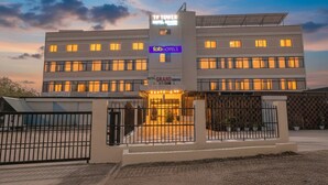 Un hôtel moderne à plusieurs étages, doté d’une entrée imposante avec une allée fermée par un portail et de panneaux solaires sur le toit.