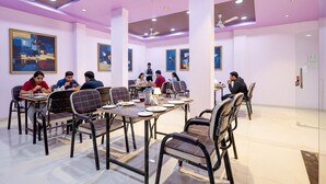 Un espace repas comprenant plusieurs tables et chaises, des ventilateurs de plafond et des œuvres d’art accrochées aux murs.