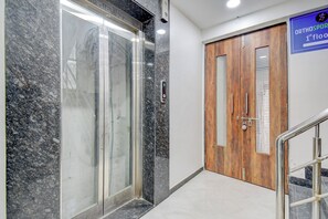 Un pasillo con pared de mármol, puerta de madera y un cartel que indica la ubicación.