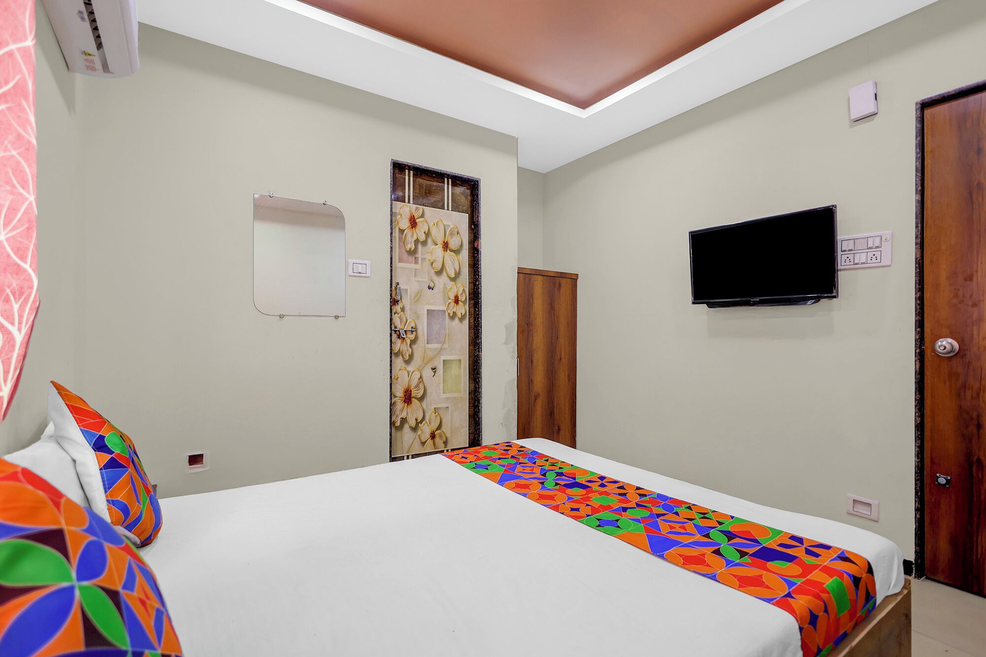 A hotel room with a bed, a television, and a wooden door.