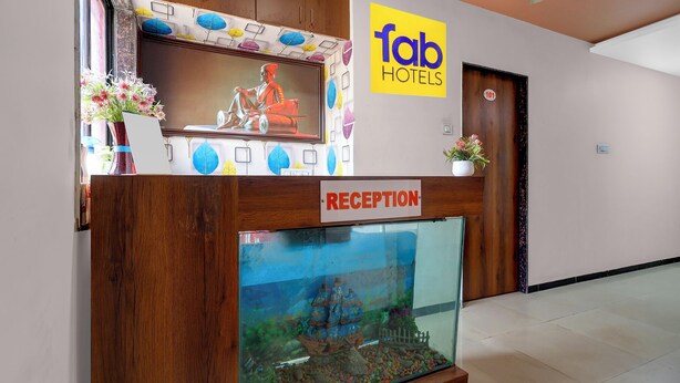 A reception area with a wooden reception desk, a reception sign, a large aquarium, and a 'fab hotels' sign on the wall. - Fabhotel Aditya Lodging (Chhatrapati Sambhajinagar)