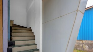 A staircase with beige steps and green edges, leading to a white wall with a visible crack. - Fabhotel Aditya Lodging (Chhatrapati Sambhajinagar)