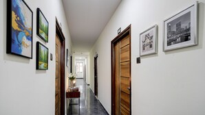 A hallway with framed artwork on the walls, a wooden door, and a marble floor. - Fabhotel High Rise Kokapet (Hyderabad)