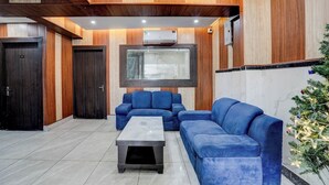 A modern living room with a sectional sofa, a coffee table, and a large TV screen. - Fabhotel Ivory Loft (Noida)