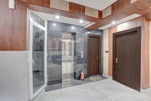 Un interior moderno con entrada por puerta de cristal, un extintor y una puerta de madera.