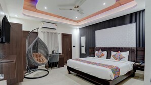 A modern bedroom with a bed, a hanging chair, a desk, and a television. - Fabhotel Ivory Loft (Noida)