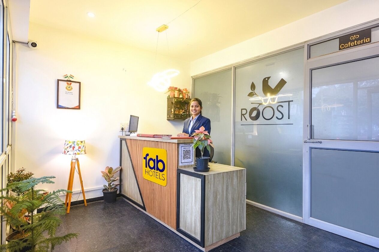 A reception desk with a sign for 'fab hotels' and a 'ROOST' sign in the background.