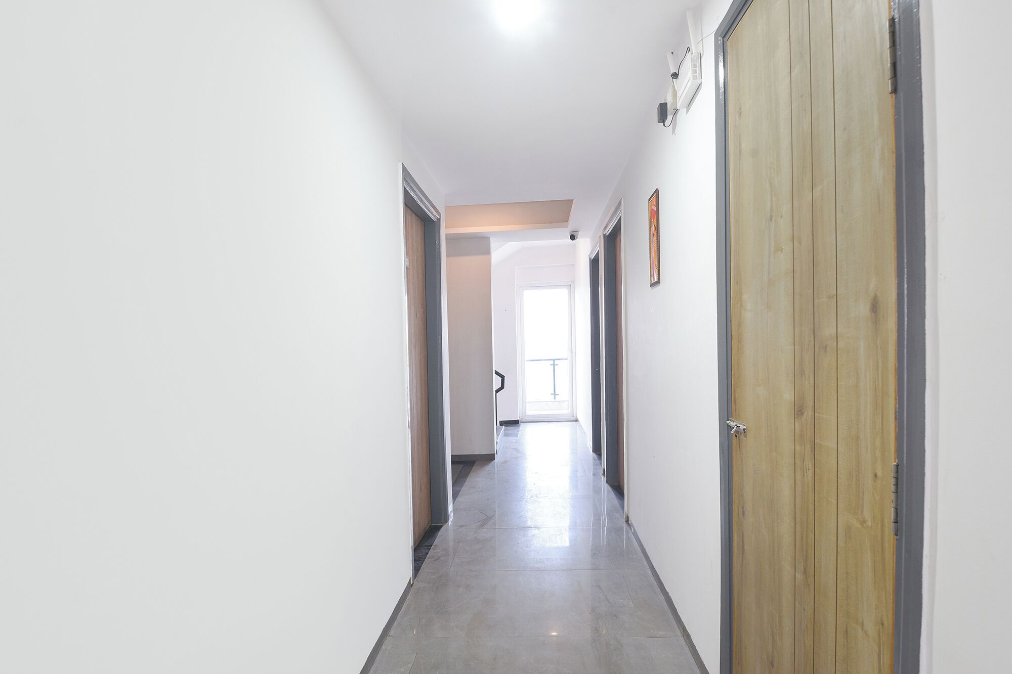 Ein Korridor mit einer Holztür, einer weißen Wand und einer Tür mit Griff.