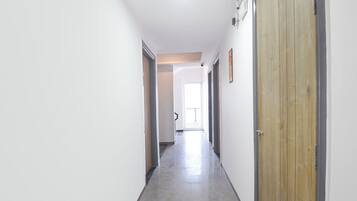 Ein Korridor mit einer Holztür, einer weißen Wand und einer Tür mit Griff.