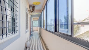 A narrow corridor with patterned flooring, large windows, and a view of buildings outside. - Fabhotel Dream Sky (Pune)