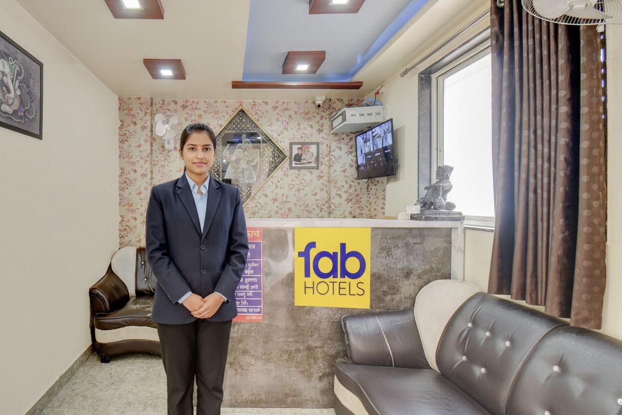 A hotel reception area with a sign reading "fab hotels," a sofa, a television, and a decorative mirror.
