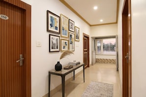 A hallway with wooden doors, numbered 150, and a table with books and a vase. - Fabhotel Continental (Barakpur)