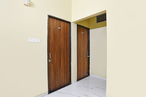 Two wooden doors with numbers 201 and 202, a light switch, and a white marble floor. - Fabhotel Mannat (Indore)