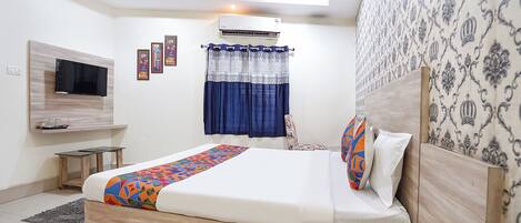 Une chambre moderne avec un lit, un téléviseur fixé au mur, un appareil de climatisation et un mur décoré d’un motif.