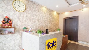 A hotel reception desk with a clock, a decorative statue, and a sign for 'Fab Hotels'. - Fabhotel Garden Tree (Bhubaneshwar)