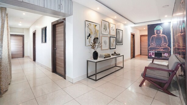 A modern hallway with a console table, framed artwork, and a large Buddha statue. - Fabhotel Garden Tree (Bhubaneshwar)