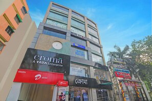 A multi-story building with various businesses including a gym, a medical center, and a bank. - Fabhotel The Crown Aura (Bidhannagar)