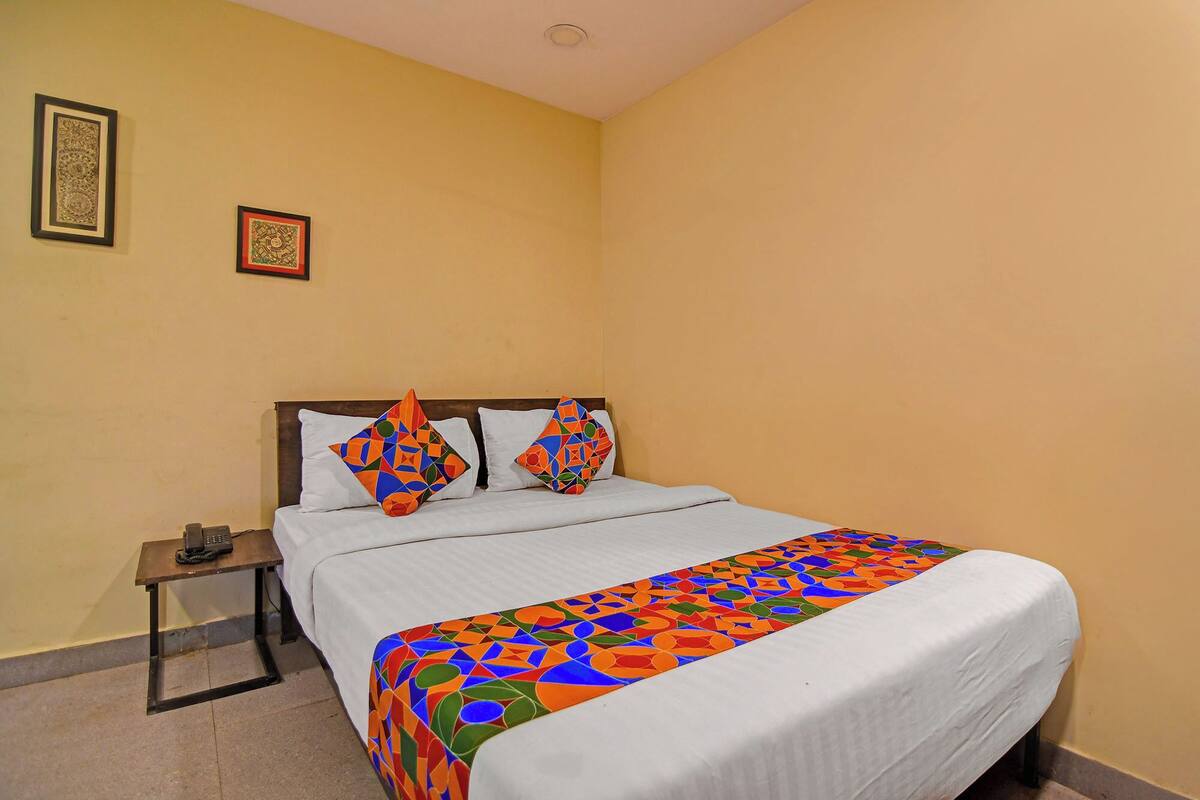 Habitación de hotel con una cama, una mesita de noche y dos cuadros en la pared.
