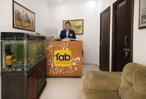 Una reception con insegna 'fab hotels', un acquario e un divano.