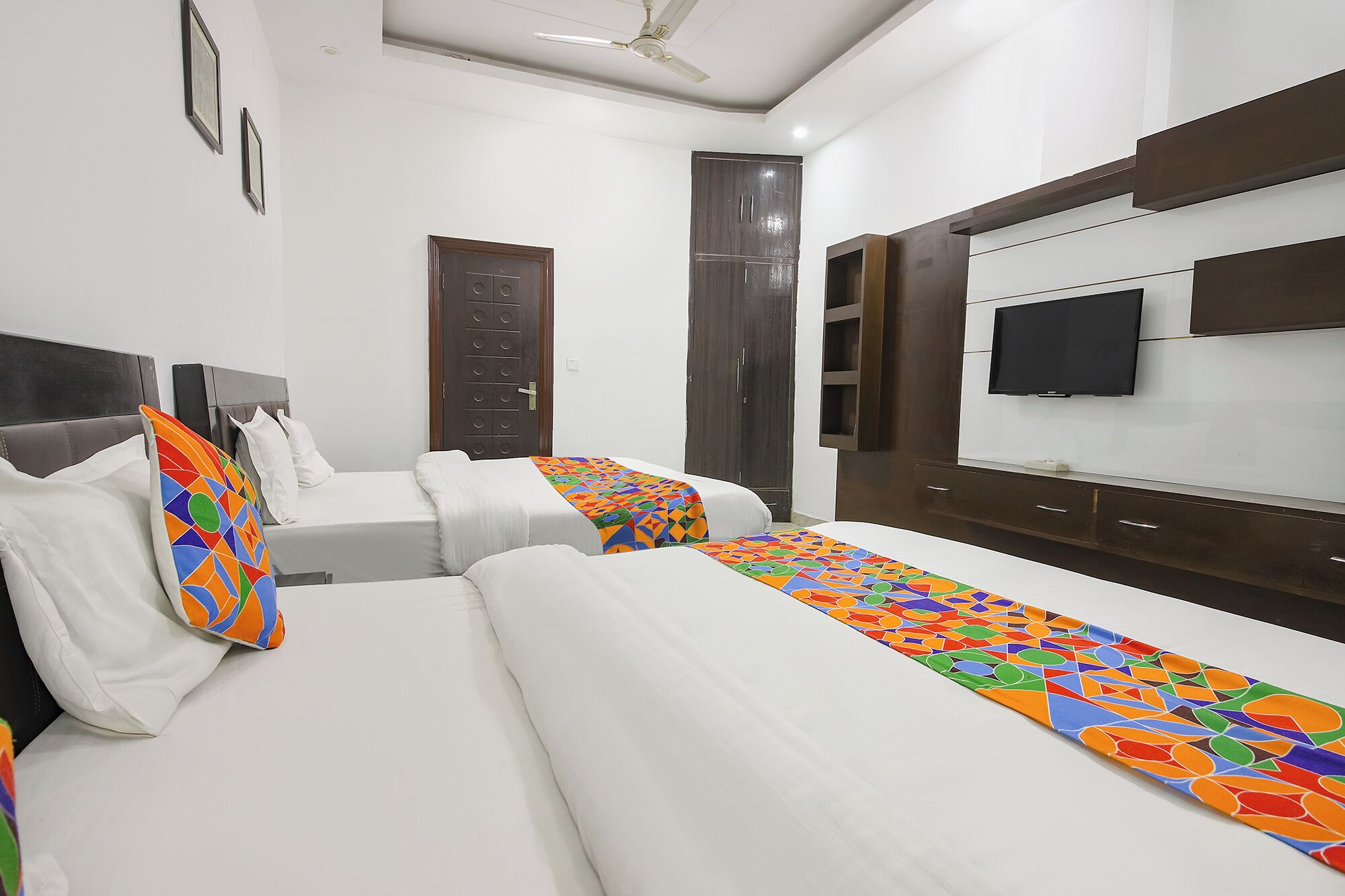 A hotel room with two beds, a television, and a wardrobe.
