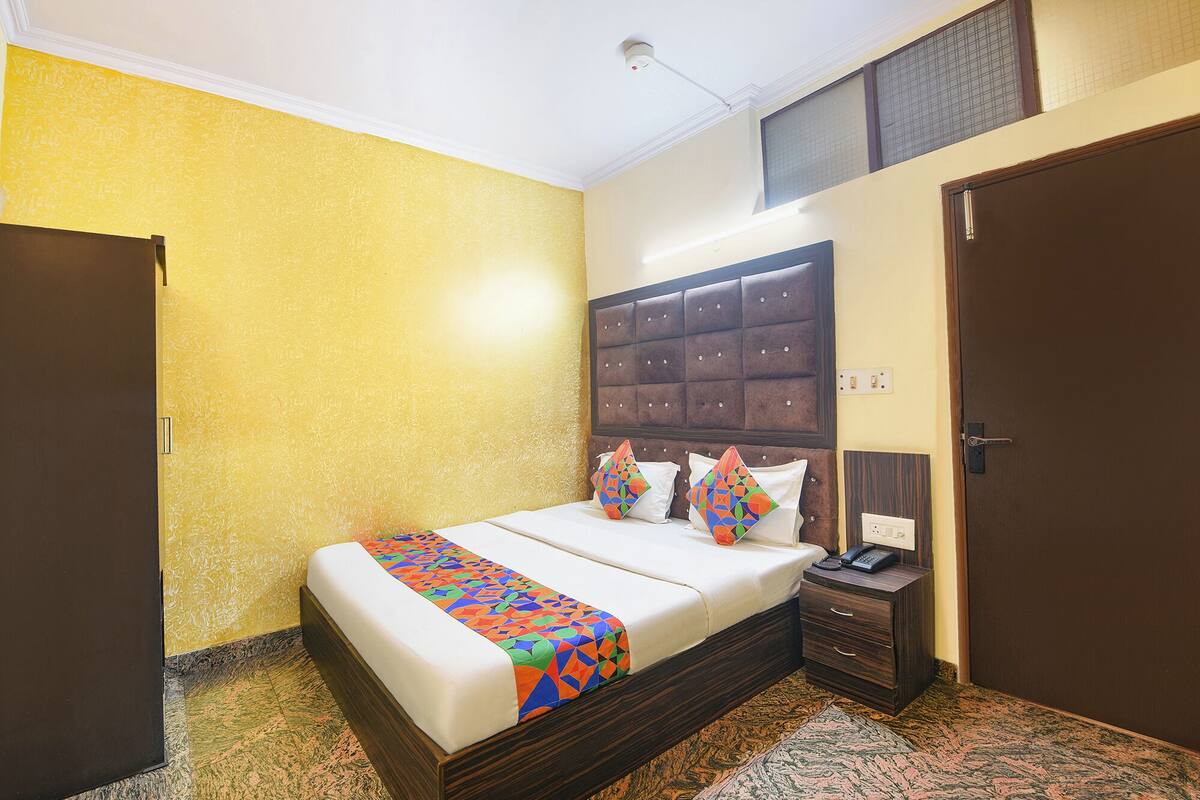 A hotel room with a bed, a nightstand, a telephone, and a door.