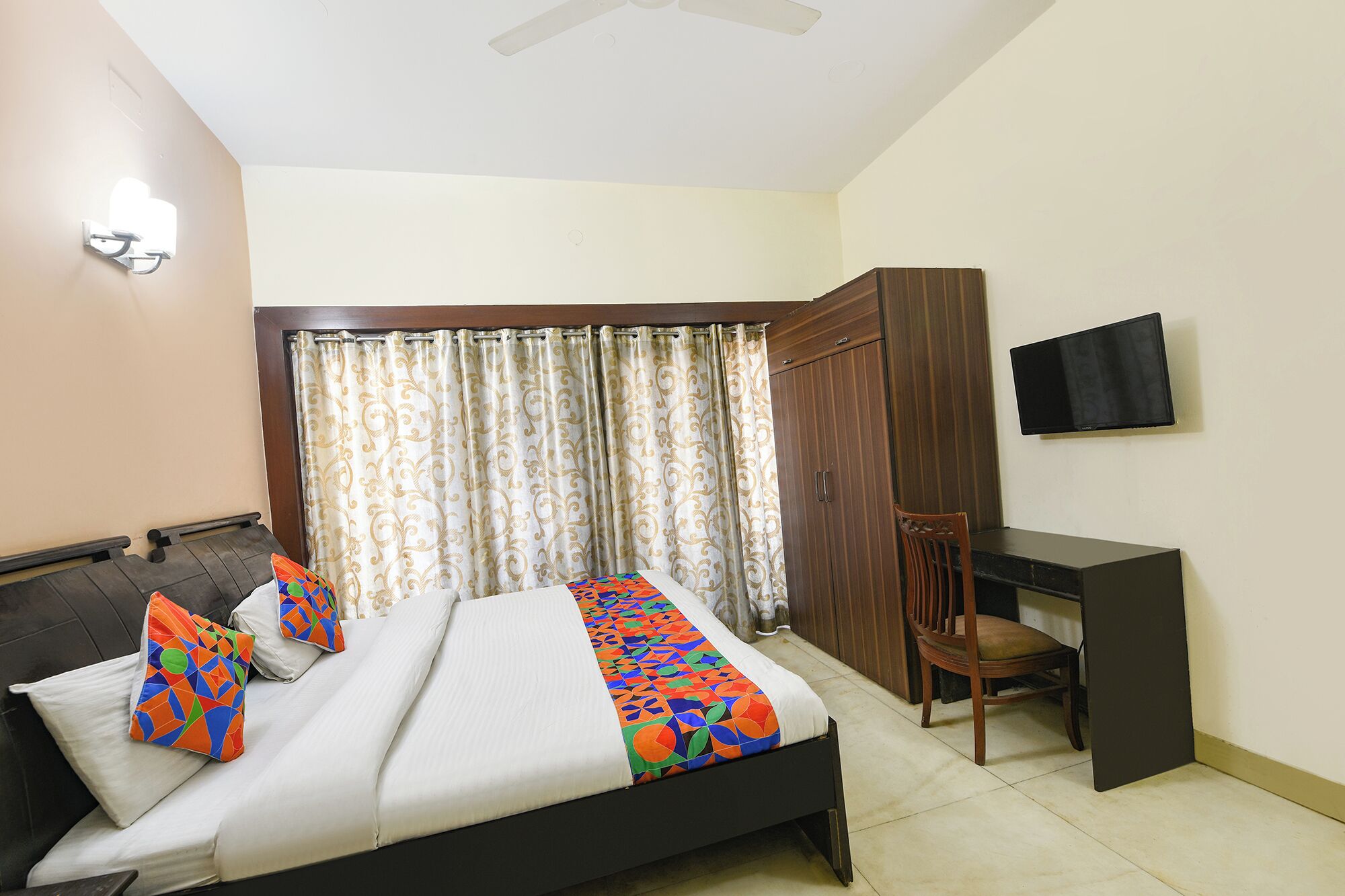 A bedroom with a bed, a desk, a chair, a TV, and a wardrobe.