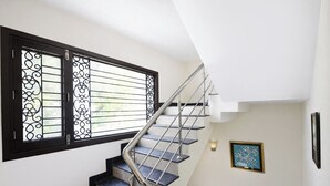 Una escalera con barandilla de metal y escalones negros que conduce a un rellano con un cuadro en la pared.