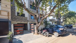 Zona residencial con un coche aparcado y un árbol en primer plano.