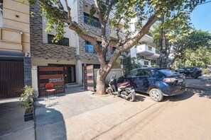 A residential area with a parked car and a tree in the foreground. - Fabhotel Le Regent (Gurugram)