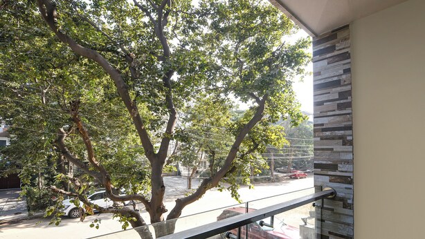 Un balcón con vista a una calle arbolada y coches estacionados.