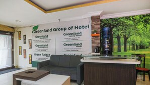 A hotel reception area with a couch, a coffee machine, and a wall with multiple hotel names and contact information. - Fabhotel Arka Residency (Jaipur)