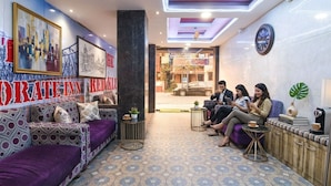 A reception area with a patterned floor, a reception desk, and a seating area with sofas and tables. - Fabhotel The Corporate Inn I (Kolkata)