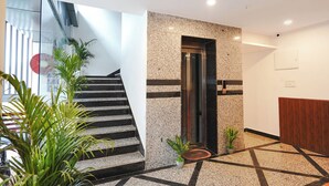 Un vestíbulo moderno con una escalera, un mostrador de recepción y una puerta que da a un ascensor.