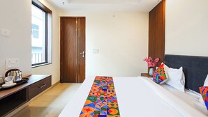 Una habitación de hotel con cama, escritorio, ventana y puerta.