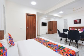 Una habitación de hotel con cama, escritorio, silla y televisor.