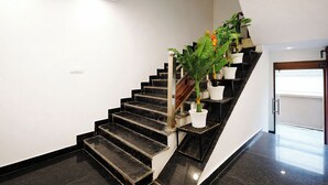 A modern staircase with black steps and white walls, leading to a door with a window.