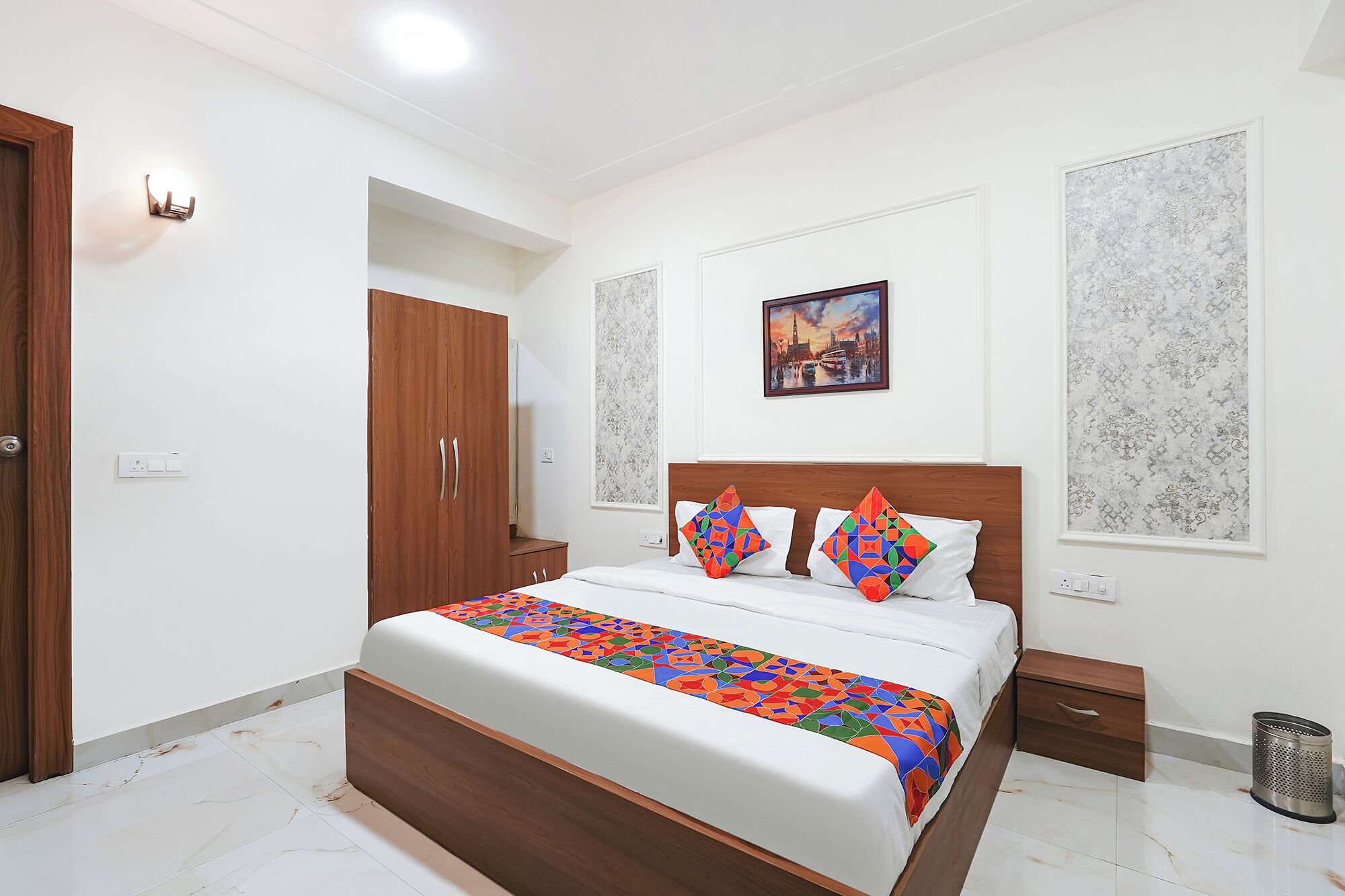 A bedroom with a wooden bed frame, white bedding, and colorful geometric pillows.