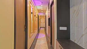A hotel hallway with wooden doors, a marble floor, and a ceiling with recessed lighting. - Fabhotel Disa (Kolkata)