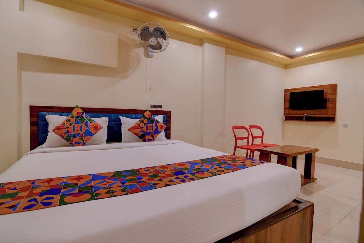 A hotel room with a bed, a TV mounted on the wall, a small table, and a chair.