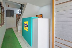 A hallway with a green mat, a door with a 'fab hotels' sign, and a staircase. - Fabhotel Ar Residency (Mumbai)
