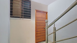 A room with a wooden door, a window with metal bars, and a metal staircase railing. - Fabhotel Ar Residency (Mumbai)