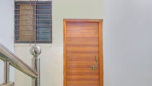 A wooden door with a brass handle and a small window with metal bars. - Fabhotel Ar Residency (Mumbai)