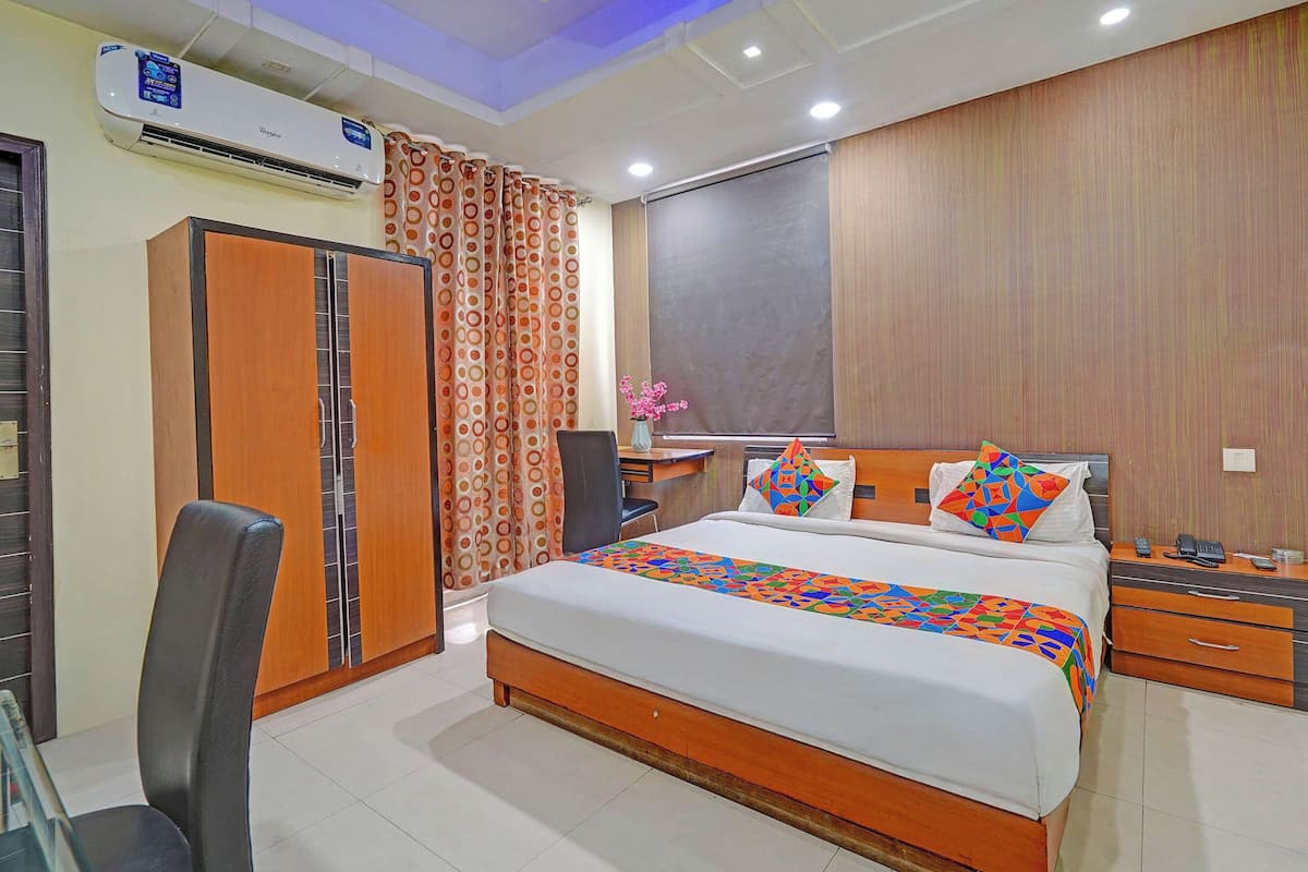 Una habitación de hotel con cama, escritorio, silla, aire acondicionado y armario.