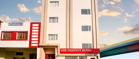 A multi-story hotel with a prominent red and white facade, a sign reading 'The Perfect Hotel,' and a 'TabHotels' logo above the entrance.